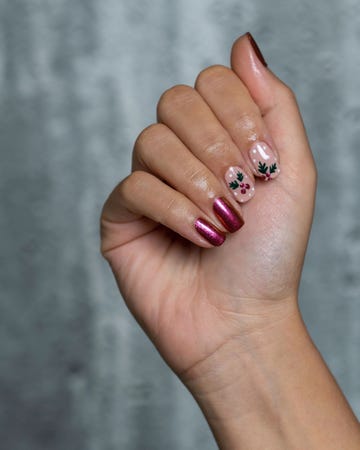 a hand with painted fingernails in a holly berry holiday motif