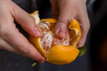 close up male hands peel tangerine