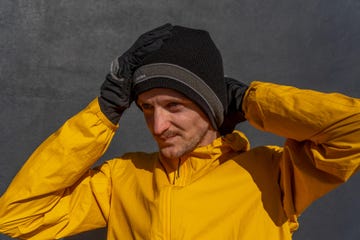 individual wearing a yellow jacket and black gloves appearing to express an emotion