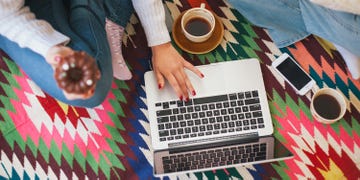 Person working on a laptop on the floor with coffee