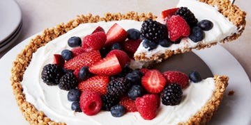 a slice of no bake fruit and granola breakfast tart topped with blueberries, blackberries, raspberries, and strawberries lifting out of the larger tart