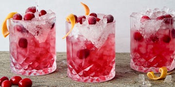 a short glass with a sugar rim, filled with a tequila grapefruit and cranberry cocktail, garnished with a grapefruit twist and fresh cranberries