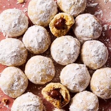 round hazelnut shortbread cookies coated in powdered sugar with nutella in the center of each cookie