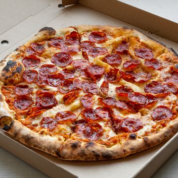 delicious italian pizza in a pizza box and a delivery box, on the table in a pizzeria sliced pizza slice with tomatoes, pepperoni sausage and cheese the concept of unhealthy lifestyle, overeating, junk food, fast food delivery to your home or work