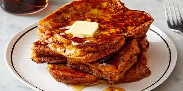 a stack of french toast on a white plate topped with butter and maple syrup