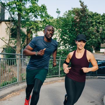 determined male and female friends jogging on bridge in city