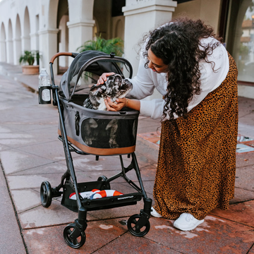 woman petting dog in pet stroller