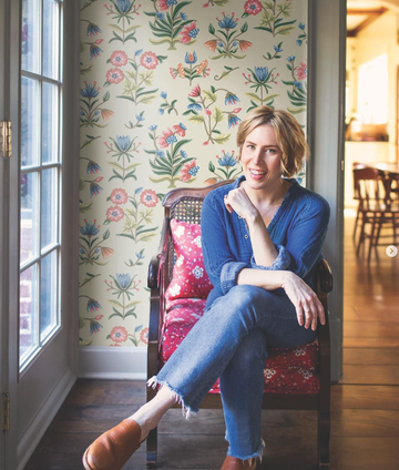 erin napier sitting in chair in front of wall with floral wallpaper