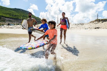 family running and splashing into sea together with body boards