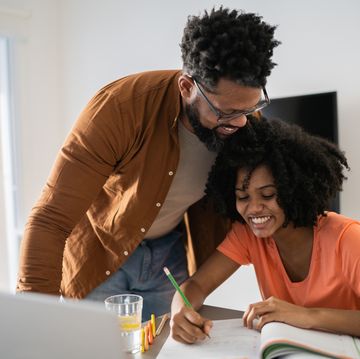 father happily helping his smiling daughter with homework