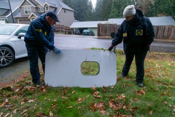 national transportation safety board agents hold up the fallen off door plug of flight 1282