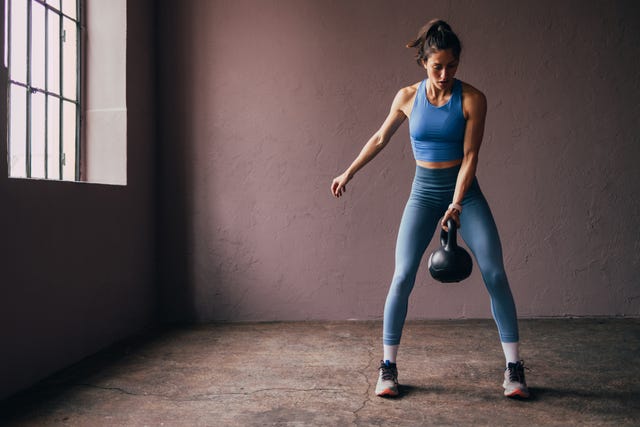 focused woman exercising with kettlebell in a gym setting