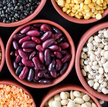 full frame image of group of eight, orange brown dishes filled with pulses, peas and beans, black beluga lentils, split yellow lentils, green peas, horse gram, red kidney beans, black eyed peas, split red lentils, butter beans, elevated view