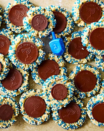 thumbprint cookies with blue and white sprinkles with a chocolate gelt coin in the center