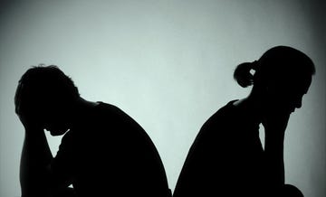 silhouettes of two people sitting apart in a tense posture