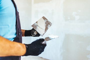 handsome construction worker finishing a facade of interior wall,