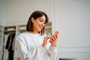 smiling businesswoman checking orders by smartphone in clothes shop