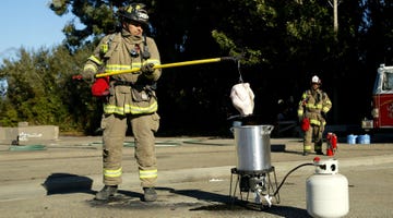 firefighter demonstrating turkey frying techniques with safety equipment