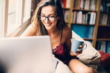 woman dressed in a sexy lingerie drinking coffee and using a laptop