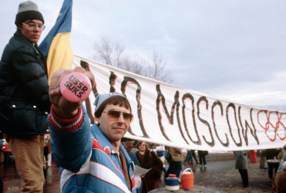 american protesters at the lake placid games opening ceremony hold various signs of protest against the russians including a sign fostering boycott of the 1980 moscow summer olympic games