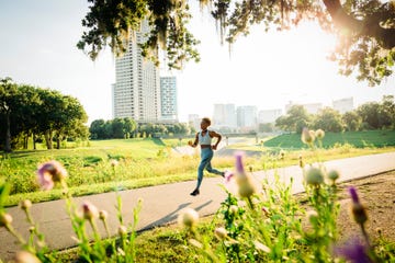 woman running on path in park beyond wildflowers