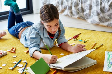 young girl on floor drawing with color pencils