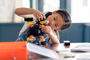 young girl adding wheel to robot