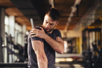 handsome young man feeling the pain in shoulder at the gym