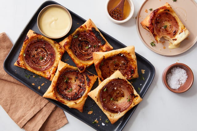 savory pastries topped with caramelized onions on a black tray