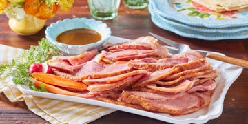 sliced ham served on a platter with sides of vegetables and sauce