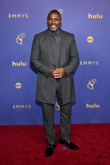 idris elba in formal attire standing on a red carpet at the emmy awards