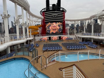 deck area of a cruise ship featuring pools seating and a large screen