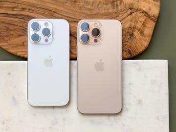 Two smartphones on a marble surface with a wooden board in the background