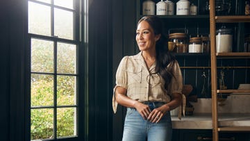 joanna gaines stands in a dark pantry looking out a window