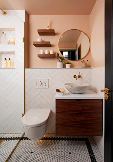 a wall hung toilet wooden vanity unit with countertop basin plus floating shelves and a round gilt edged mirror