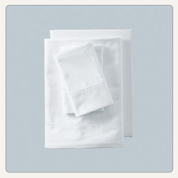 set of neatly stacked white bed linens including a fitted sheet flat sheet and pillowcases