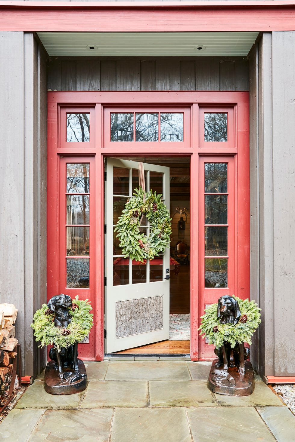 entrance with a red door and two dog statues adorned with wreaths