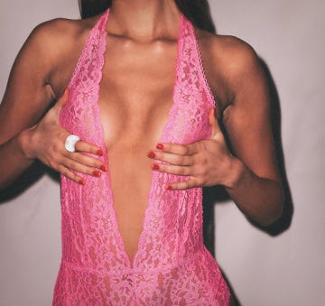 a model wearing a pink lace outfit posing with both hands near her chest