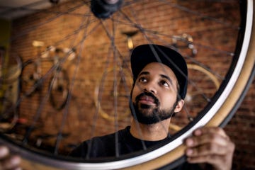 man examining bicycle wheel while standing in workshop