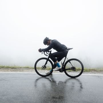 man relaxing on bicycle at wet street in foggy weather