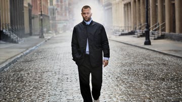 person walking down a wet cobblestone street in an urban setting