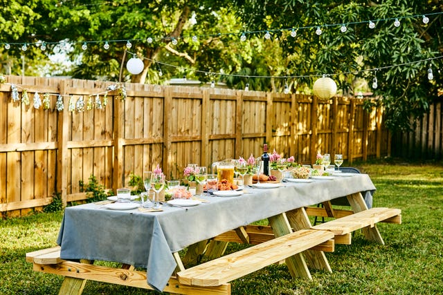 picnic table set up in a garden with floral decor and food