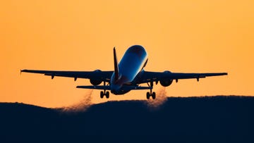 rear view silhouette of an airplane taking off at sunset