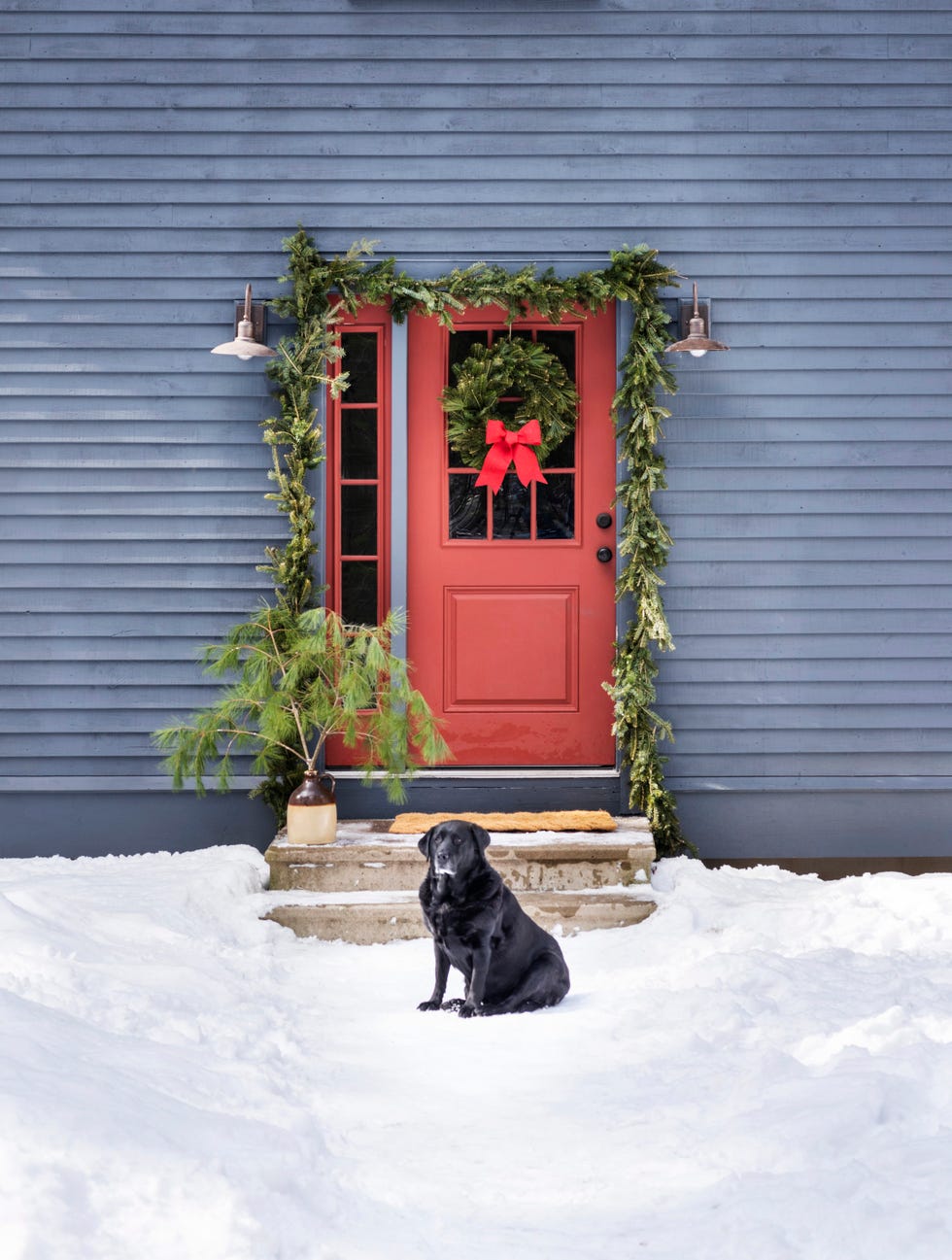 gray saltbox home with red front door decorated for christmas