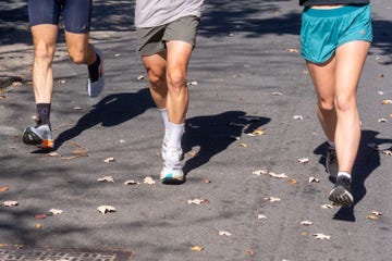 three runners moving along a street with fallen leaves