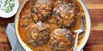 ground beef patties in a pan with mushroom gravy