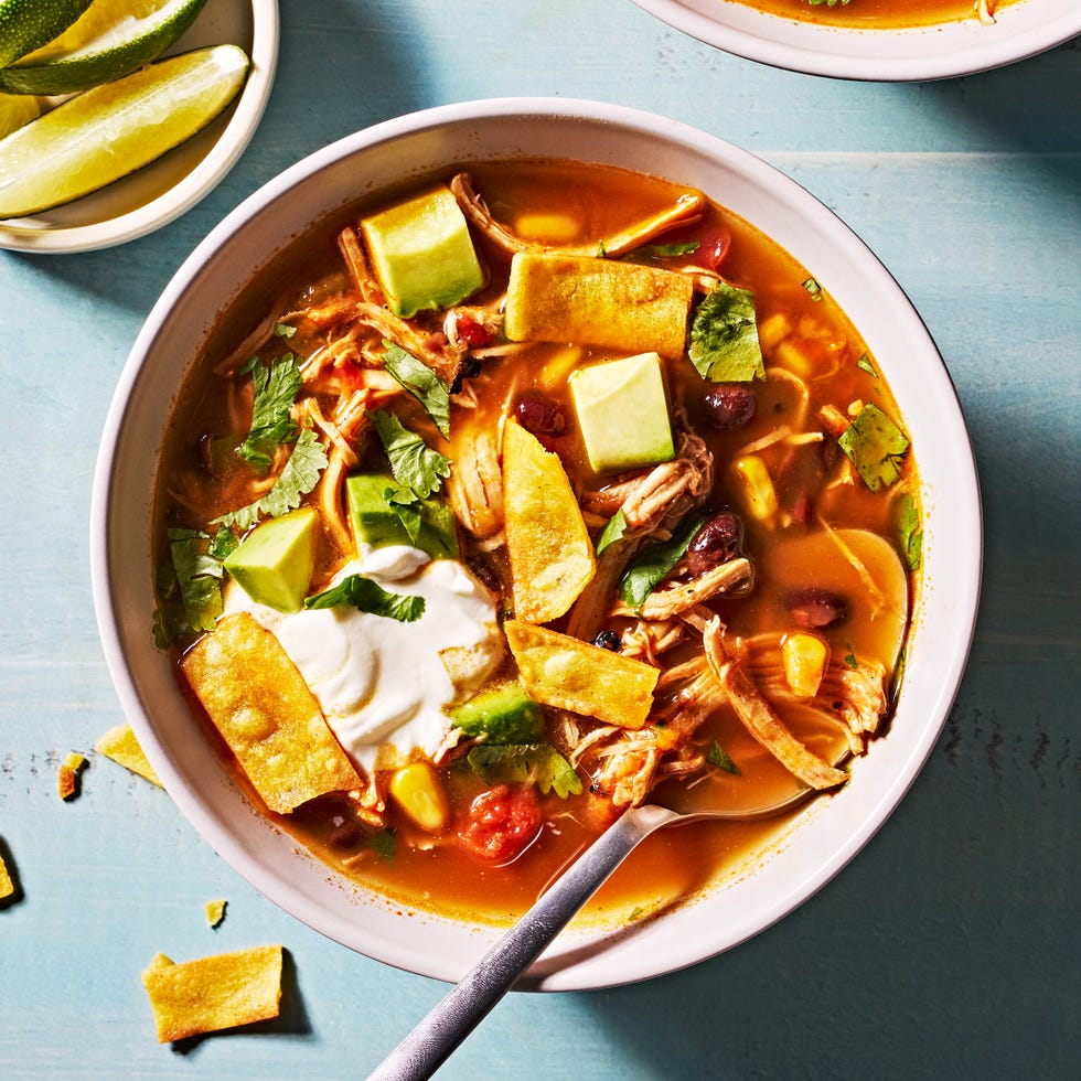 slow cooker chicken tortilla soup with sour cream, avocado slices, cheese and tortilla strips