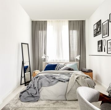 small bedroom interior with king size, mirror, and black and white photos on the wall