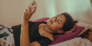 a woman looking at her phone and lying on a bed