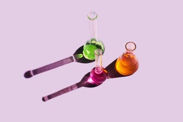 laboratory glassware with multicolored liquids on purple background natural medicine, cosmetic research, bioscience, organic skin care products top view, flat lay